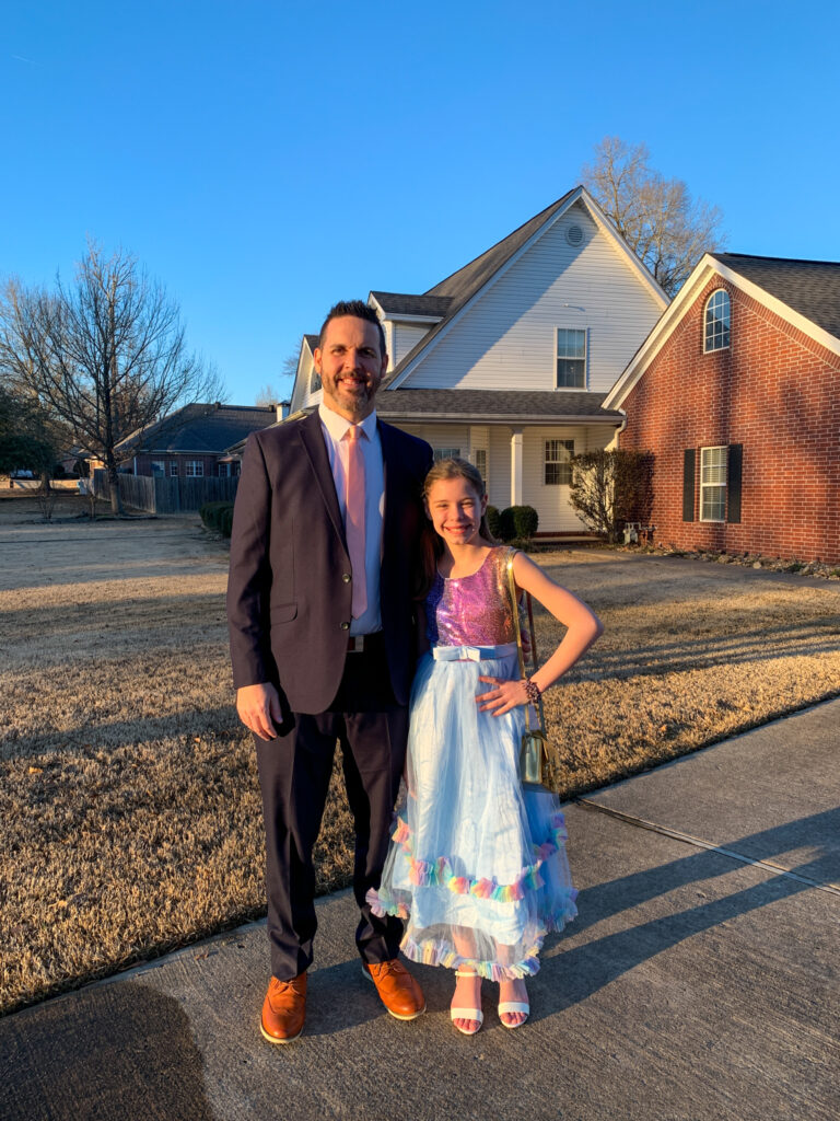 Daddy and daughter dressed up in Daddy Daughter Dance outfits in front of house