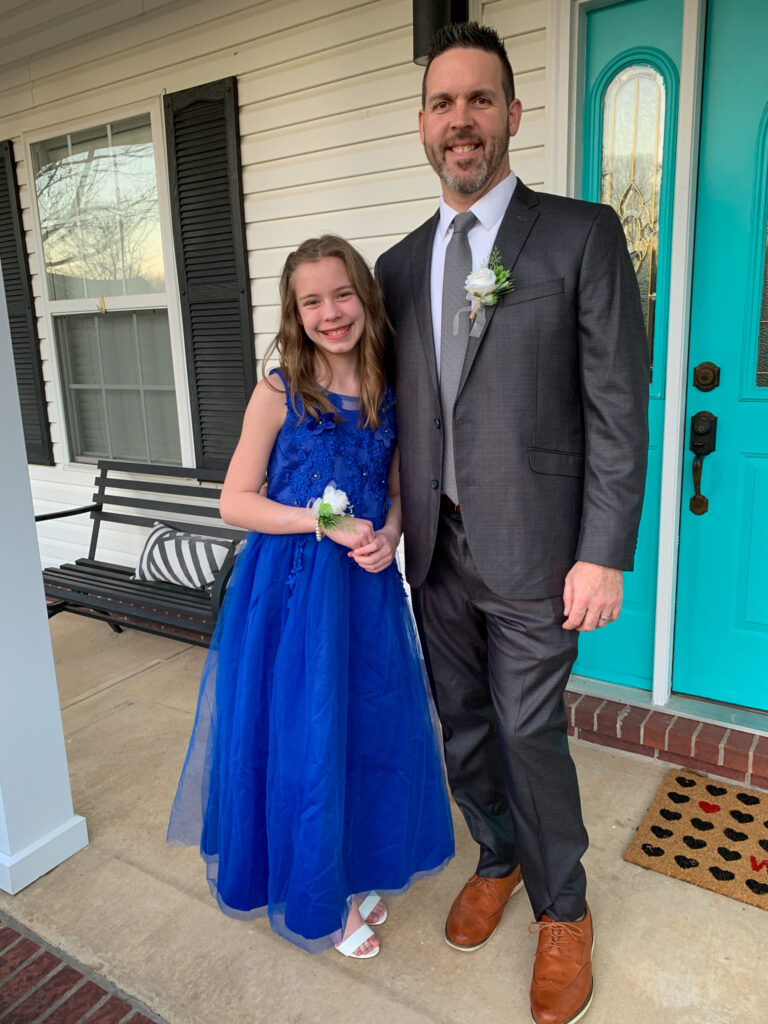 man and girl stand together on porch before school event