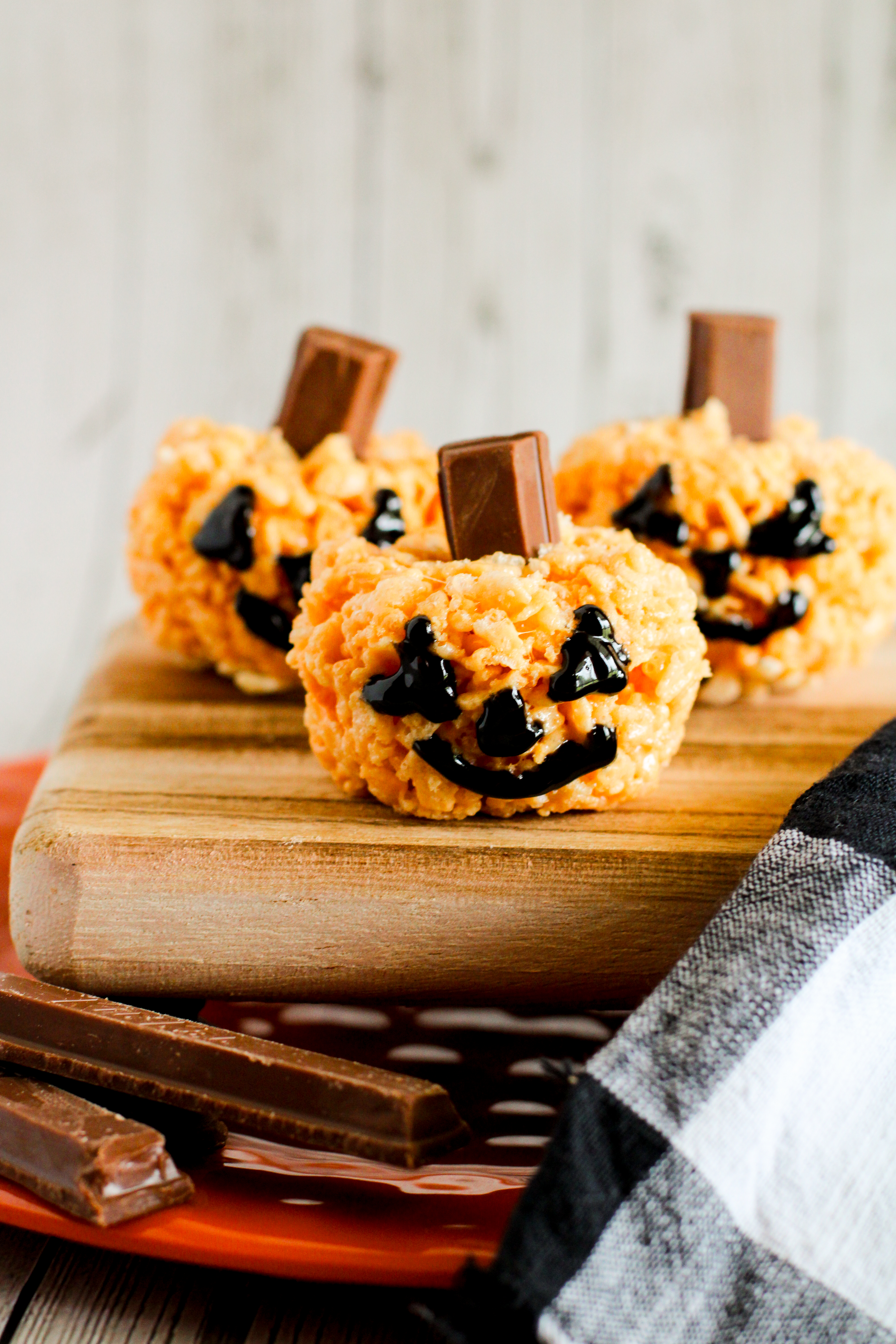 three Halloween jack o'lantern Rice Krispie treats stacked on plates