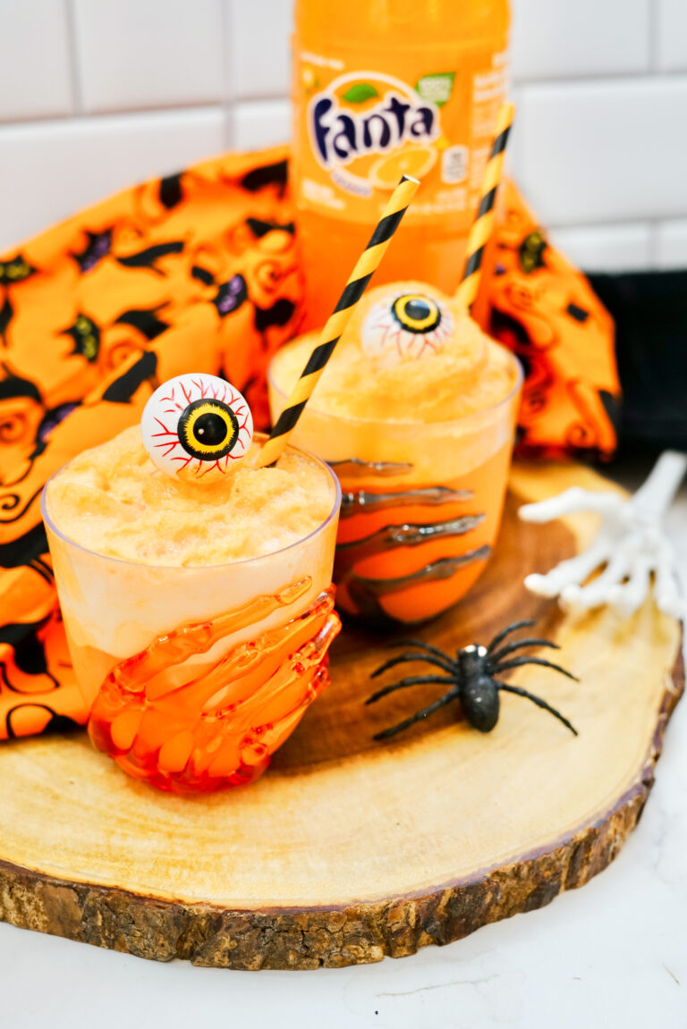 orange Fanta floats with sherbet for Halloween with Halloween skeleton hands and eyeballs
