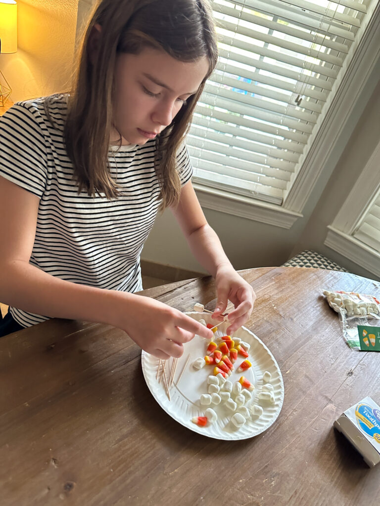 girl makes Candy Corn tower with marshmallows with a Halloween STEM kit