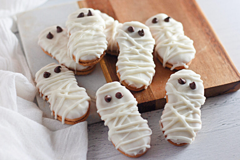 Nutter Butter mummies on top of a cutting board with a white cloth