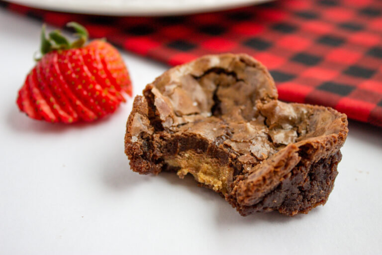 heart shaped brownies with Reese's Peanut Butter Cups in center on counter by strawberry