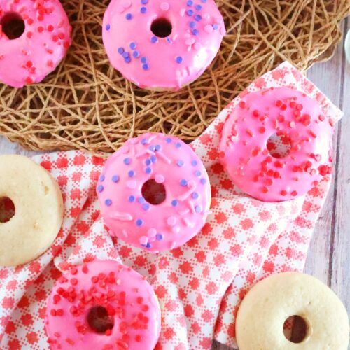 pink donuts with pink vanilla icing and some unglazed donuts on plaid cloth