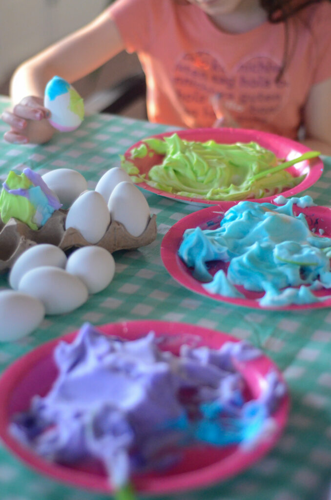 little girl makes food coloring Easter eggs with Cool Whip
