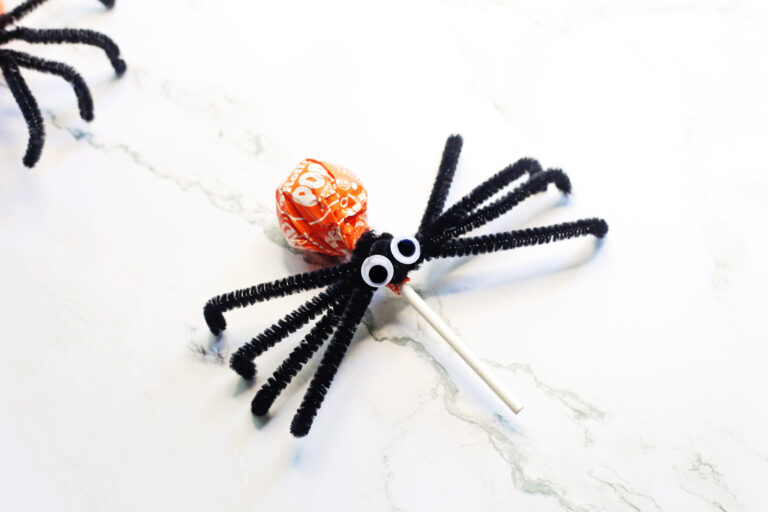 Halloween spider lollipops crafts with pipe cleaner and googley eyes on white counter
