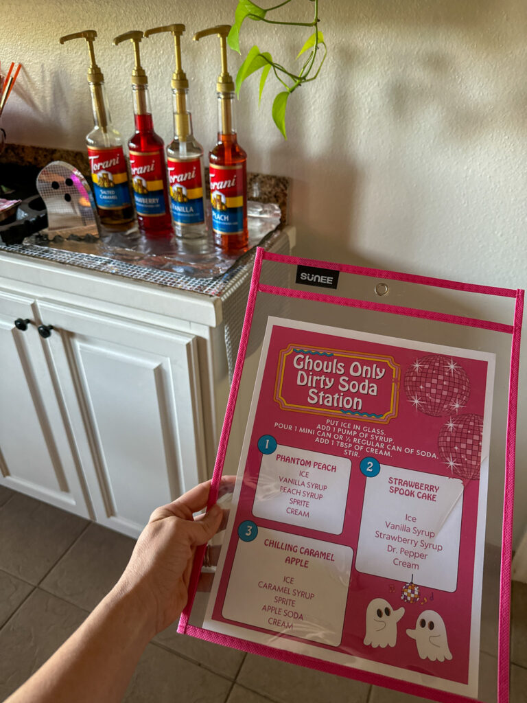 woman holds Halloween Dirty Soda menu in hand for girls' Let's Glow, Ghouls party