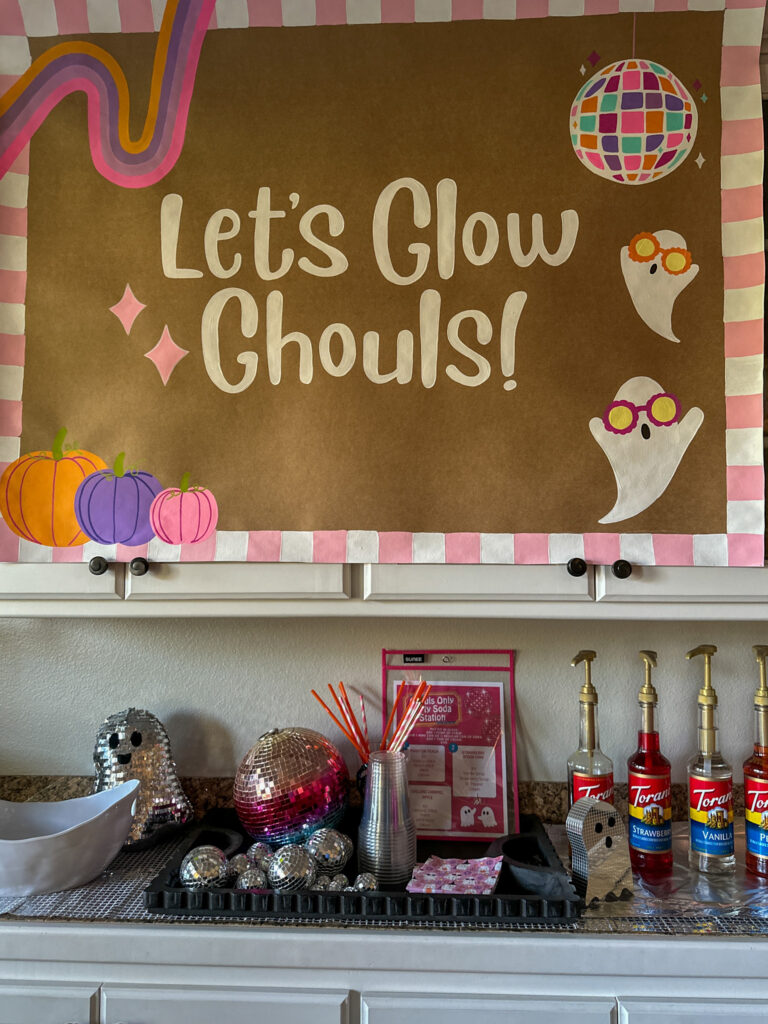 Let's Glow, Ghouls disco Halloween banner for teen party hangs above a drink station