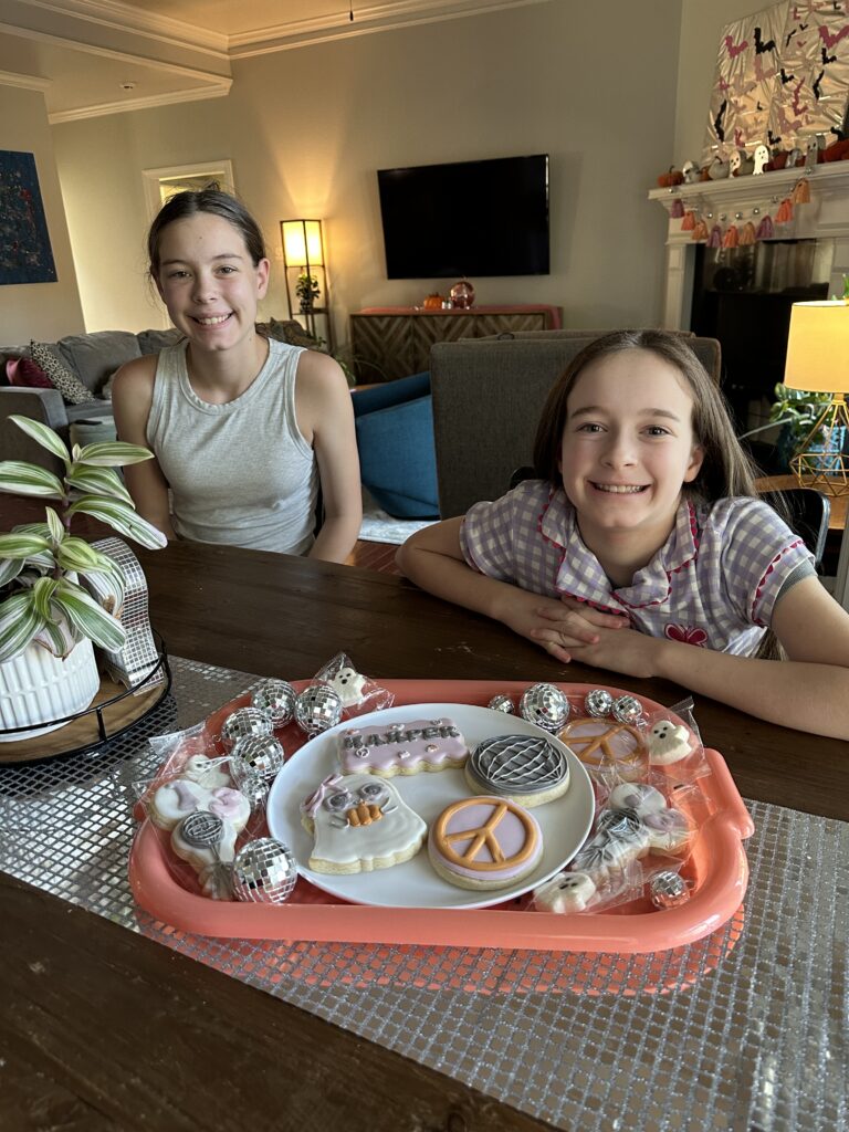 Arkansas bloggers, Harper and Norah, from Arkansas Girls Blog sit behind a tray of custom disco ghost cookies by Cookies by Jenna